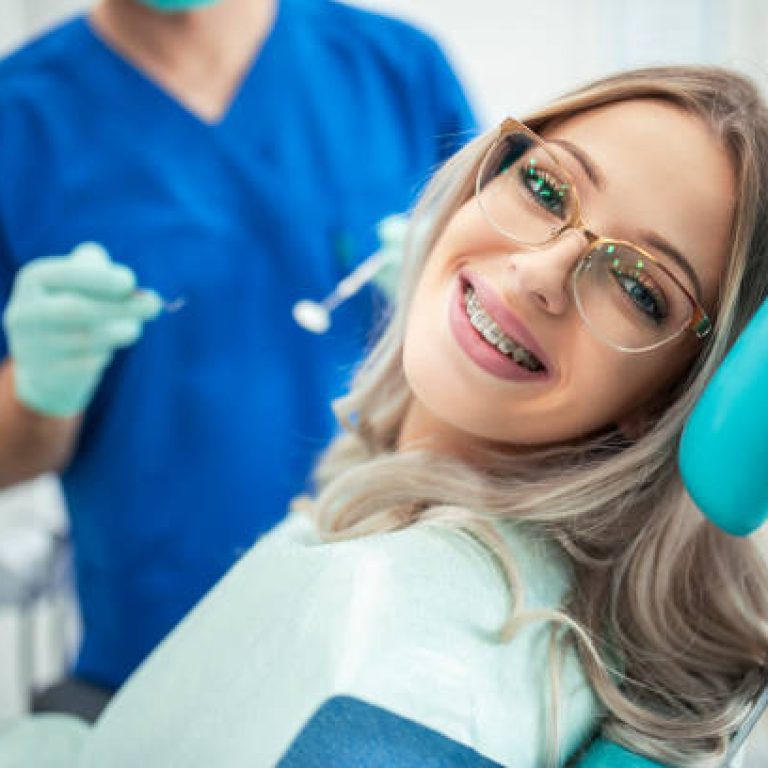 Beautiful young woman with braces having dental treatment at dentist's office